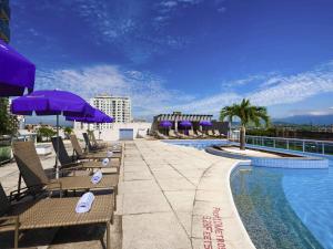 a swimming pool with chairs and umbrellas on a resort at Mercure Rio de Janeiro Nova Iguaçu in Nova Iguaçu