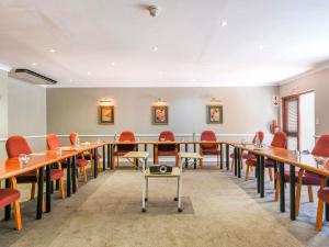 a conference room with long tables and red chairs at Mercure Hotel Bedfordview in Johannesburg +80 photos