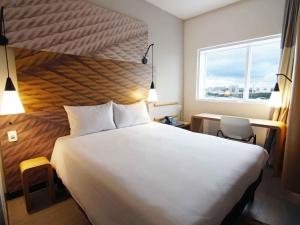 ein Schlafzimmer mit einem großen weißen Bett und einem Fenster in der Unterkunft ibis Osasco in Osasco