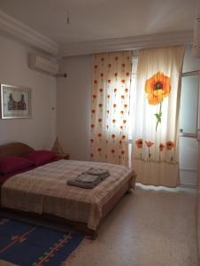 a bedroom with a bed and a window with a flower curtain at Room Flower Near Airport in Ariana