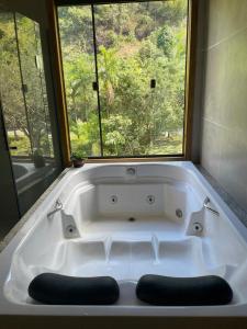 La salle de bains est pourvue d'une baignoire blanche et d'une fenêtre. dans l'établissement Casa das Pedras - Um recanto de paz em Santa Tereza, à Santa Teresa 35 autres photos