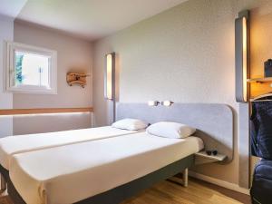 Una cama en una habitación con dos almohadas encima. en ibis budget Versailles Chateau Saint cyr l'Ecole, en Saint-Cyr-lʼÉcole