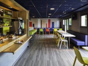 un restaurante con mesas y sillas coloridas en una cafetería en ibis budget Versailles Chateau Saint cyr l'Ecole, en Saint-Cyr-lʼÉcole