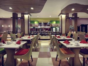 a dining room with tables and chairs and a restaurant at Mercure Pontianak City Center in Pontianak