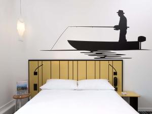 a bedroom with a bed with a boat on the wall at ibis Styles Macon Centre in Mâcon