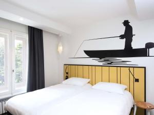 a bedroom with two beds and a boat on the wall at ibis Styles Macon Centre in Mâcon +66 photos