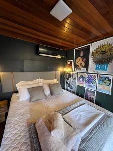 a bedroom with a large bed with pillows and posters at Casa Jasmim em Domingos Martins a 5km do Centro in Domingos Martins