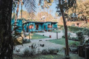a blue house in the middle of a forest at Chalé Climatizado com banheira em frente ao Parque do Passaúna em Curitiba by Tiny House Passaúna in Curitiba