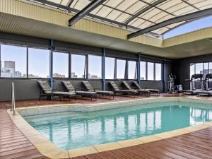 a large swimming pool with chairs and windows at Mantra on Hay Perth in Perth