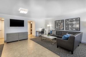 a living room with a couch and a flat screen tv at Best Western Palm Beach Lakes in West Palm Beach