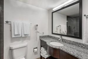 a bathroom with a toilet and a sink and a mirror at Best Western Palm Beach Lakes in West Palm Beach +55 photos