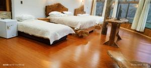 a bedroom with two beds and a wooden floor at Altos quiñenahuin lodge in Curarrehue