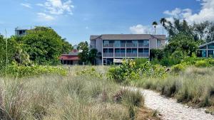 a building in front of a field of tall grass at Siesta Sunset - 524 (PH) in Siesta Key