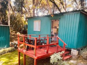 a green tiny house with a wooden deck at Container Climatizado com deck em frente ao Parque do Passaúna by Tiny House Passaúna in Curitiba