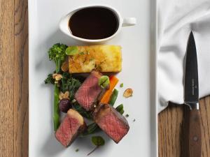 un plato de comida con carne y verduras y una taza de café en Fable Terrace Downs Resort by MGallery, en Windwhistle 35 fotos más