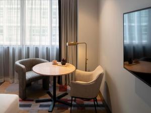a room with a table and chairs and a window at The Sebel Sydney Martin Place in Sydney
