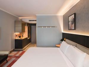 a bedroom with a large bed and a kitchen at The Sebel Sydney Martin Place in Sydney