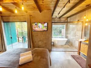 a bedroom with a large bed and a tub in a bathroom at Chalé Climatizado, com banheira e varanda em frente ao Parque do Passaúna em Curitiba by Tiny House Passaúna in Curitiba