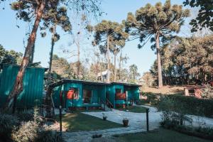 a green tiny house in a forest with palm trees at Chalé Climatizado, com banheira e varanda em frente ao Parque do Passaúna em Curitiba by Tiny House Passaúna in Curitiba