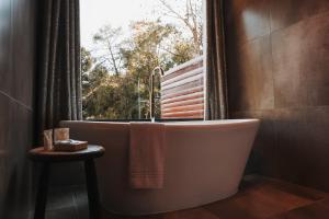 a bath tub in a bathroom with a window at Chalé Climatizado, com banheira e varanda em frente ao Parque do Passaúna em Curitiba by Tiny House Passaúna in Curitiba