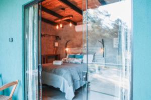 a glass door leading to a bedroom with a bed at Chalé Climatizado, com banheira e varanda em frente ao Parque do Passaúna em Curitiba by Tiny House Passaúna in Curitiba +29 photos