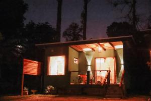 a small house is lit up at night at Chalé Climatizado, com banheira e varanda em frente ao Parque do Passaúna em Curitiba by Tiny House Passaúna in Curitiba