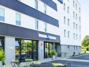 a building with tables and chairs in front of it at ibis budget Tours Nord in Tours