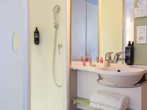 a bathroom with a sink and a shower with a mirror at ibis Budget Paris La Villette 19ème in Paris +40 photos