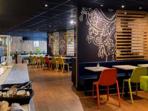 a dining room with tables and chairs and a wall at ibis Budget Paris La Villette 19ème in Paris