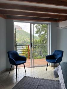two blue chairs in a bedroom with a large window at The Manzi Villa in Hartbeespoort