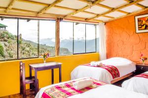 a room with two beds and a table and windows at La Granja del Colca in Cabanaconde