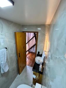 a bathroom with a toilet and a sink and a door at Chalé Industrial Pedra do Imperador in Nova Friburgo