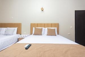 a bedroom with two beds with a remote control on the bed at Hotel Bossanova in Rionegro