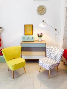 a yellow chair and a desk with a clock on the wall at L'alcova di Garibaldi in Ostuni