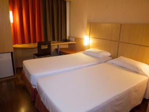 Una habitación de hotel con dos camas y un escritorio. en ibis Contagem Ceasa, en Contagem 76 fotos más