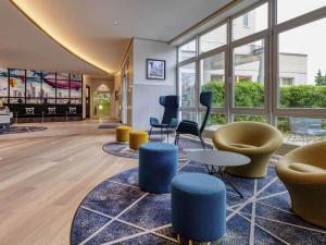 a lobby with chairs and tables and windows at Mercure Neu-Isenburg in Neu Isenburg