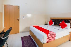 a bedroom with a large bed with red pillows at Capital O Crosswind Gold in Indirapuram