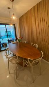 a dining room table with chairs and a wooden wall at Apto paraíso praia dos anjos in Arraial do Cabo