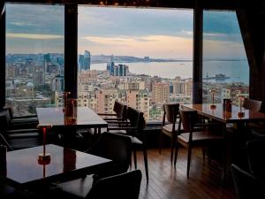 a restaurant with tables and chairs and a view of the city at Mercure Baku City in Baku
