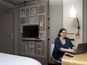 une femme assise sur un bureau avec un ordinateur portable dans l'établissement ibis Paris porte de Bercy, à Charenton-le-Pont