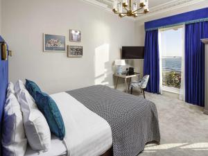 a bedroom with a bed and a desk and a window at Mercure Brighton Seafront Hotel in Brighton & Hove