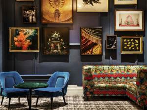 a living room with a couch and a table and pictures at Mercure Brighton Seafront Hotel in Brighton & Hove