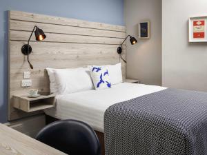 a bedroom with a bed and a chair and lights at Mercure Brighton Seafront Hotel in Brighton & Hove +132 photos
