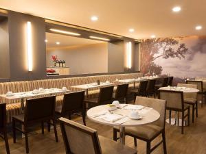 a dining room with tables and chairs and a painting at Mercure Sao Jose dos Campos in São José dos Campos