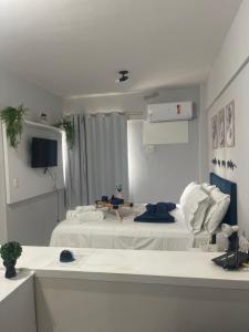 a white room with two beds and a television at Manaíra Flat 206 Em frente ao shopping Manaíra in João Pessoa
