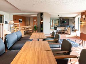 Un restaurante con mesas y sillas de madera en una sala. en IBIS STYLES Rouen Parc Expos Zenith, en Saint-Étienne-du-Rouvray