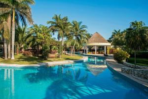 a swimming pool with palm trees and a house at Iberostar Waves Paraíso del Mar - All Inclusive in Puerto Morelos