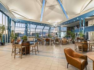 Un restaurante con mesas, sillas y ventanas. en Mantra Bunbury, en Bunbury