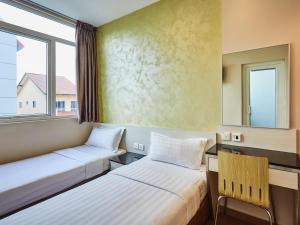 two beds in a room with a window and a chair at ibis budget Singapore West Coast in Singapore +30 photos