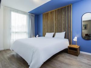 a bedroom with a large white bed and a blue wall at Aparthotel Adagio Montpellier Centre Comedie in Montpellier